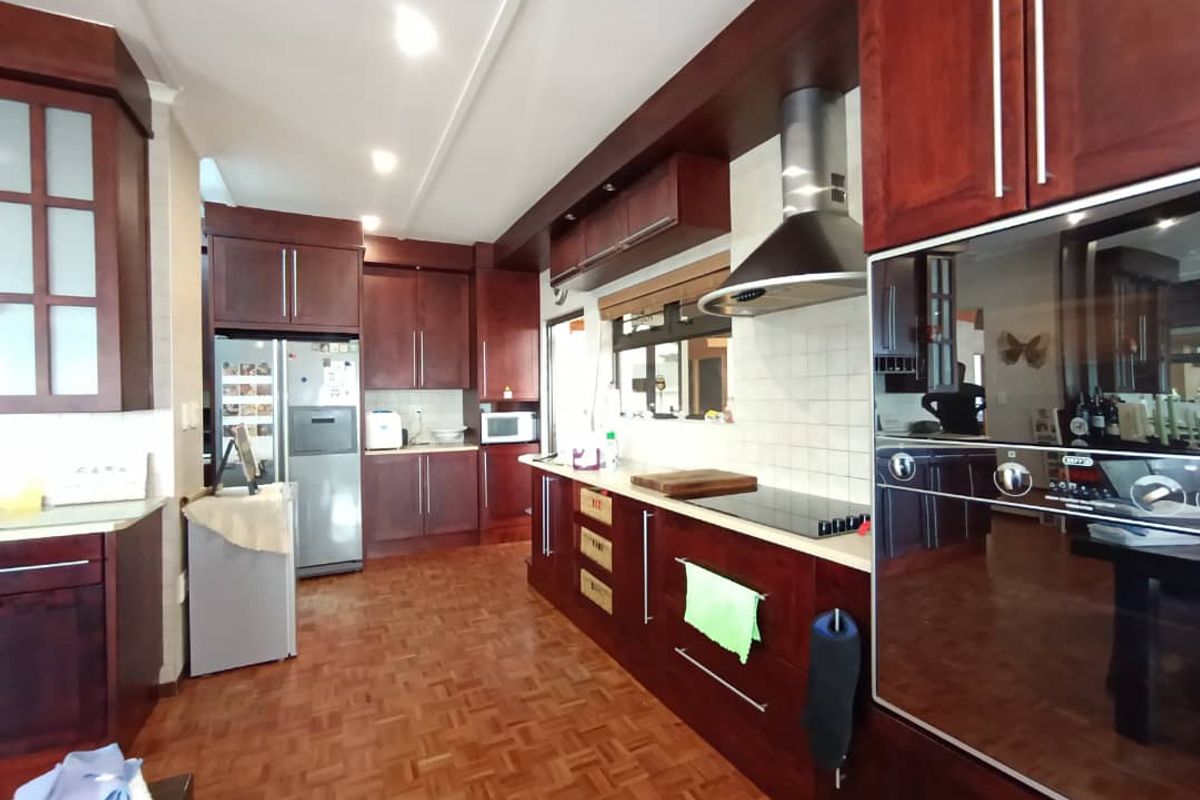 A functional kitchen featuring dark wood cabinetry, a built-in oven, a stainless steel extractor fan, and parquet flooring.