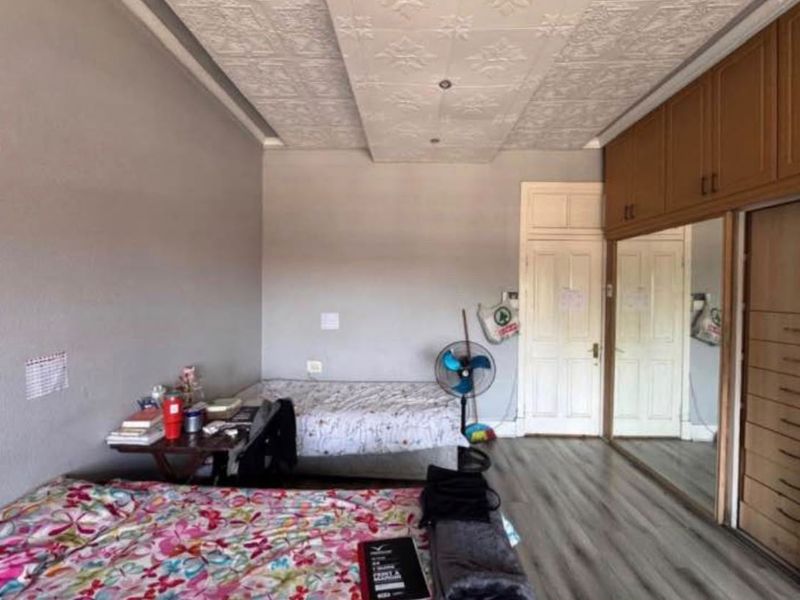 Spacious bedroom featuring laminate flooring, decorative ceiling detailing, and extensive built-in cupboards with mirrored sliding doors.