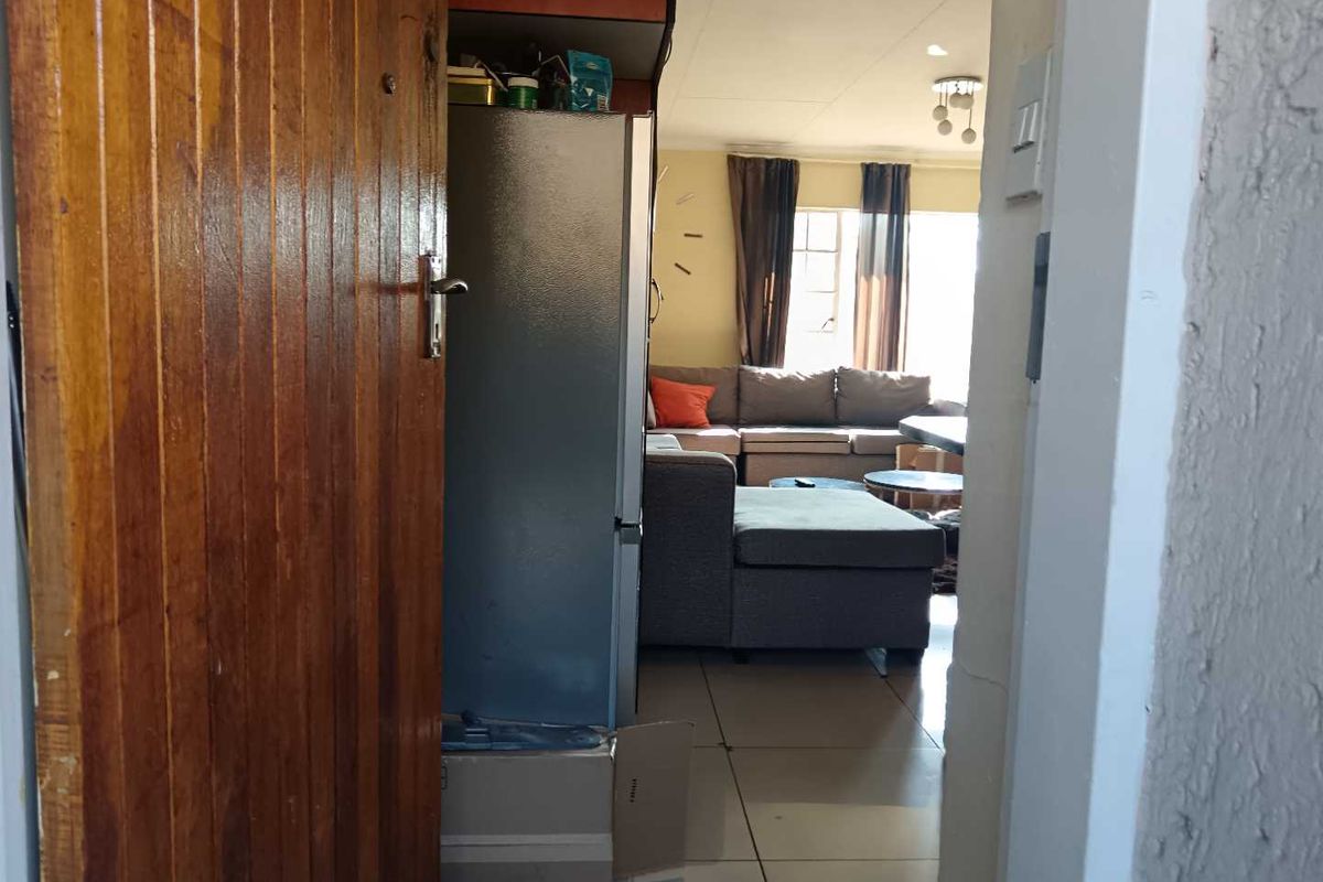 View from the doorway into an open-plan living area featuring tiled flooring and a timber entrance door.