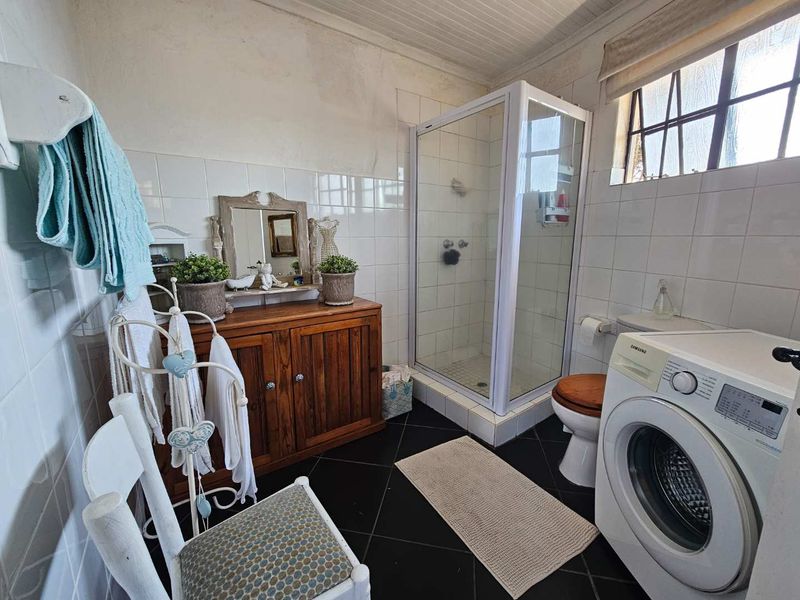A functional bathroom featuring a shower enclosure, toilet, and tiled finishes, requiring some cosmetic updates to the walls and ceiling.