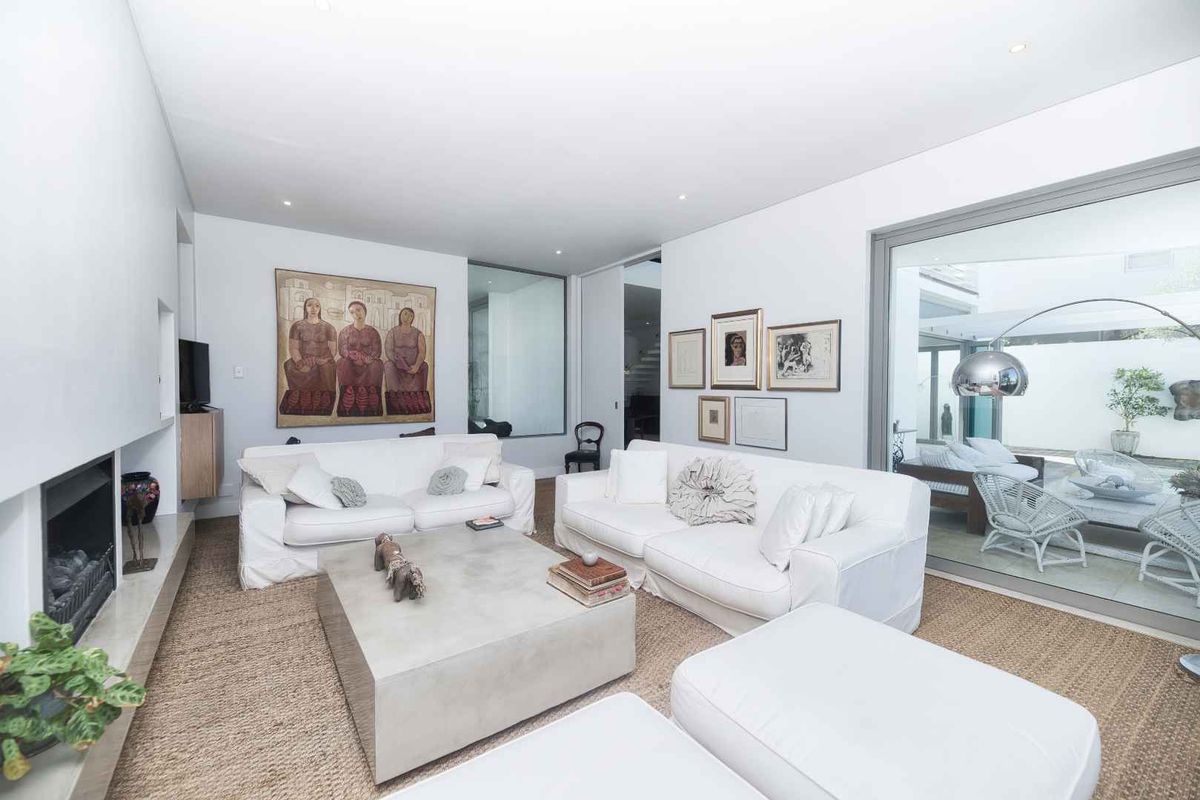 Bright and modern living room featuring a built-in fireplace, recessed lighting, and large sliding glass doors opening to an outdoor patio area.