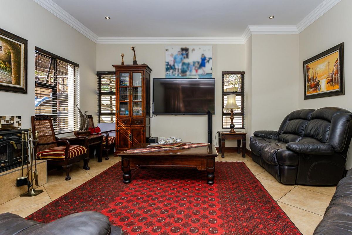 A comfortable living room featuring tiled flooring, crown molding, recessed lighting, and a built-in fireplace with a tiled surround.