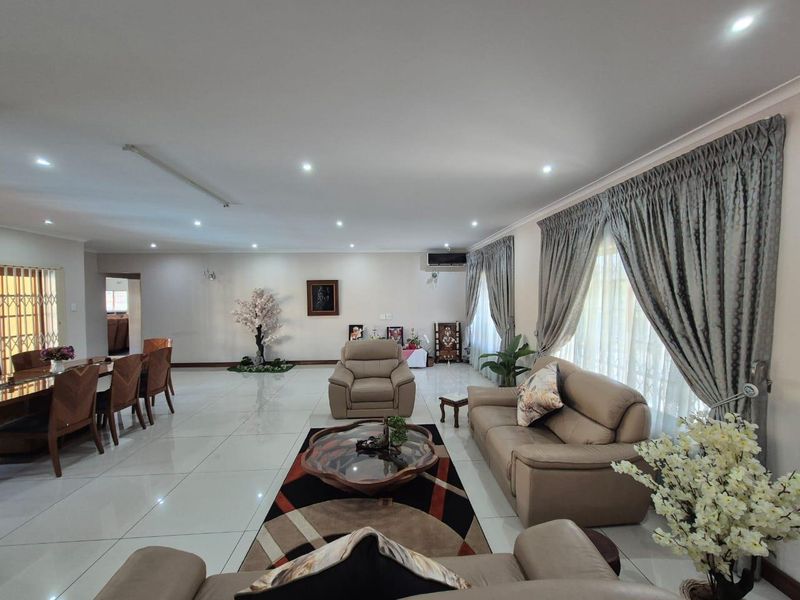 Spacious open-plan living and dining area featuring polished tiled flooring, recessed downlighting, and large windows with integrated curtain tracks.