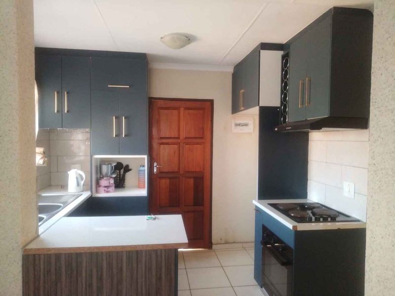 A functional kitchen featuring dark cabinetry, a built-in oven and hob, tiled backsplash, and tiled flooring, providing a practical workspace.