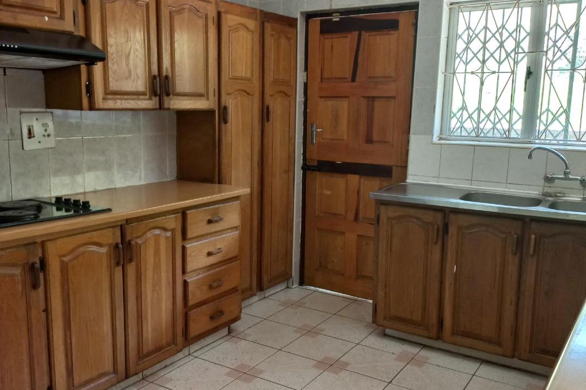 A functional kitchen featuring traditional wooden cabinetry, a double sink, built-in hob, and direct access to the exterior via a stable door.