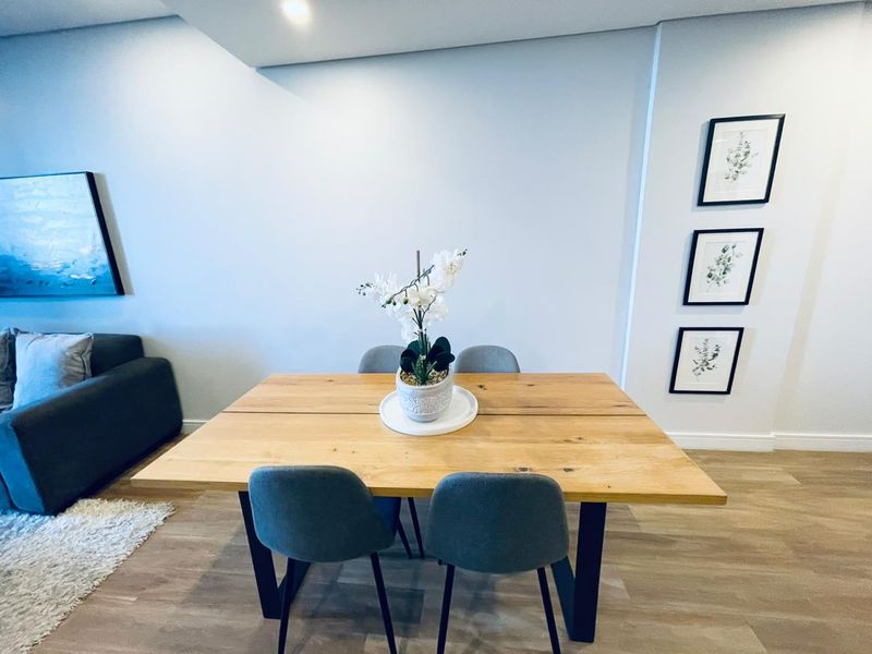 A well-maintained dining area featuring modern recessed ceiling lighting and light-toned laminate flooring, creating a bright and inviting space.