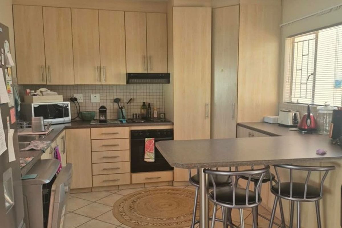 Functional kitchen featuring light wood cabinetry, laminate countertops, a built-in oven with extractor fan, tiled flooring, and a convenient breakfast nook.
