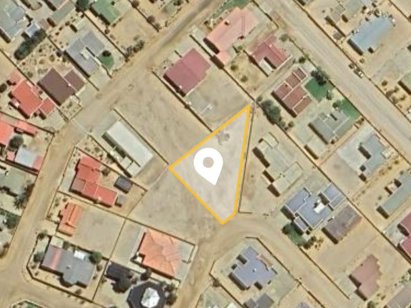 An aerial view of a vacant residential land parcel situated within an established neighborhood, highlighting the property boundaries and surrounding street layout.