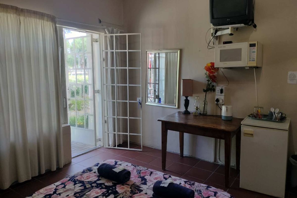 A guest bedroom featuring tiled flooring, a security gate leading to the exterior, and basic built-in wall-mounted appliances.