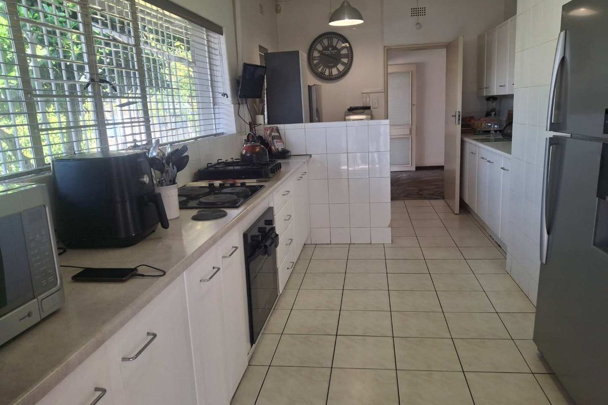 Functional kitchen featuring white cabinetry, tiled flooring, built-in oven and hob, and ample counter space with natural light from large windows.