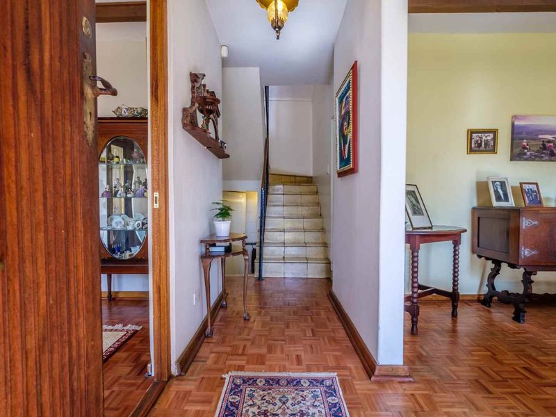 Welcoming entrance hall featuring classic parquet flooring and a staircase leading to the upper level.