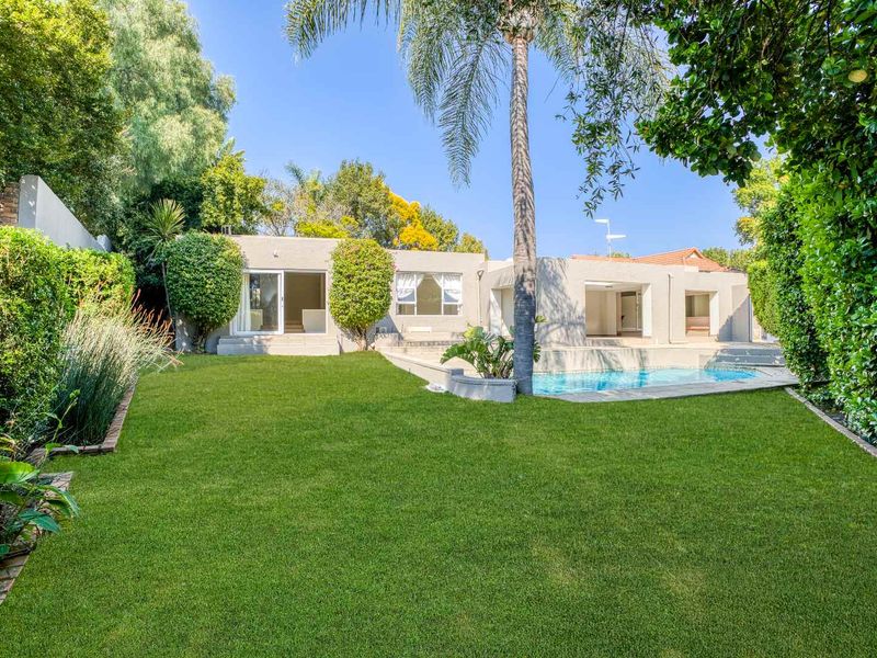 A well-maintained rear garden featuring a swimming pool, paved surround, and direct access to the home through multiple sliding glass doors.