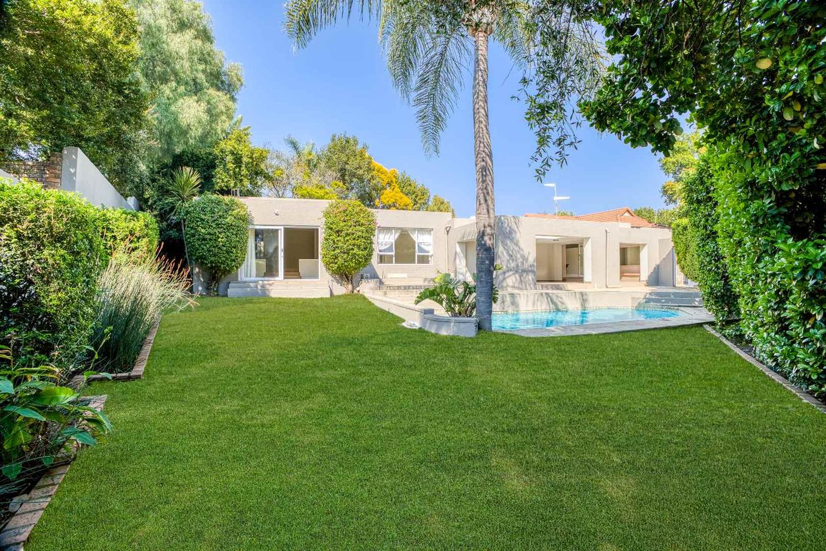 A well-maintained rear garden featuring a swimming pool, paved surround, and direct access to the home through multiple sliding glass doors.