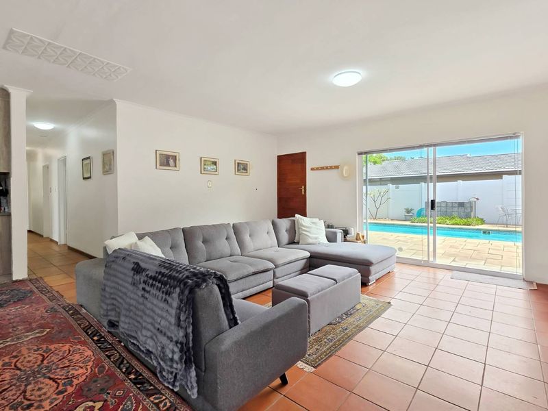 Spacious living room featuring ceramic tile flooring and large sliding glass doors providing direct access to the outdoor pool area.