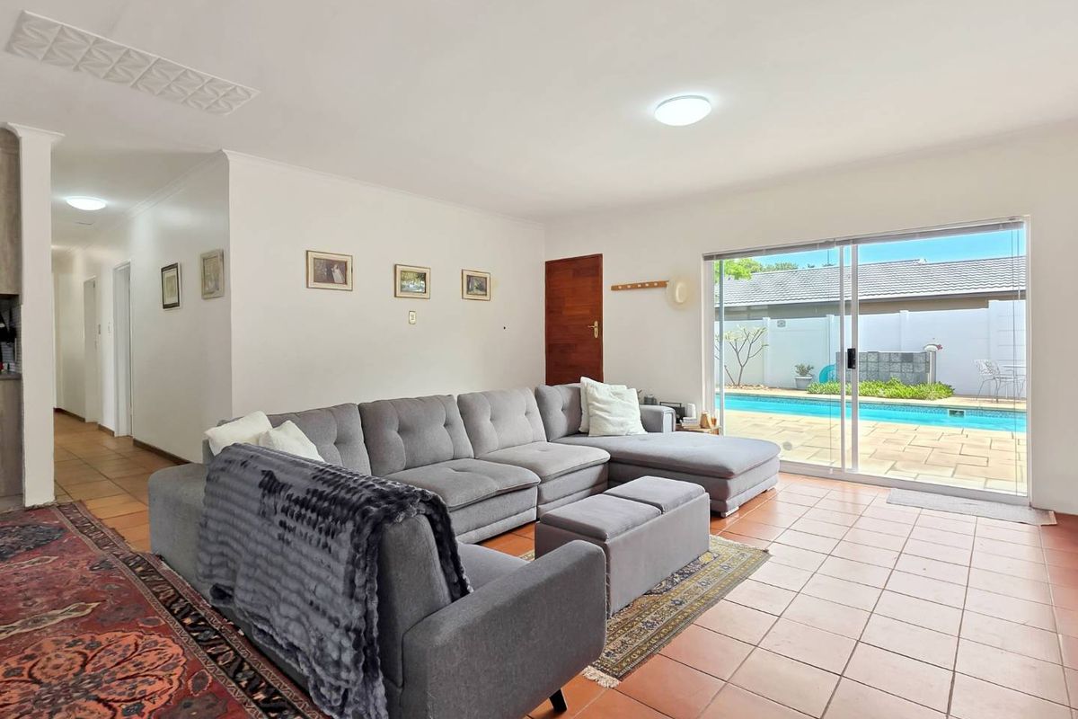 Spacious living room featuring ceramic tile flooring and large sliding glass doors providing direct access to the outdoor pool area.