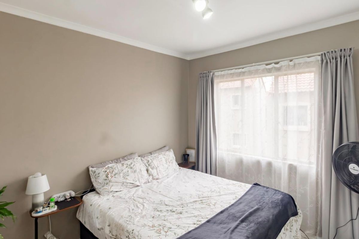 A neutrally painted bedroom featuring a large window with curtain tracks and coving detail.