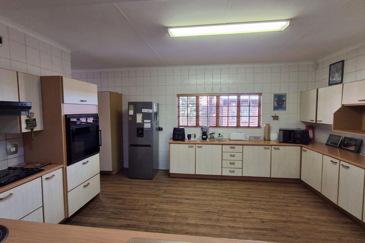 Spacious kitchen featuring extensive built-in cabinetry, laminate flooring, tiled splashbacks, and integrated appliances including an oven and hob.