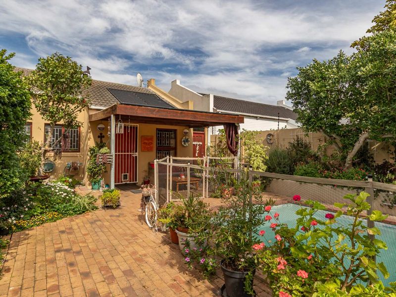 Rear exterior view featuring a paved patio area, a swimming pool with a safety net, and a covered outdoor space with solar panels.