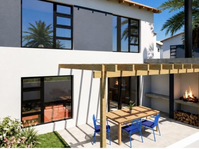 Rear exterior view of a modern townhouse featuring a paved patio, timber pergola, and a built-in braai area.