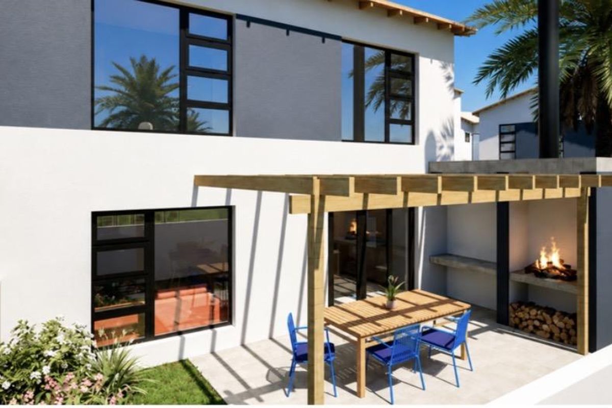 Rear exterior view of a modern townhouse featuring a paved patio, timber pergola, and a built-in braai area.