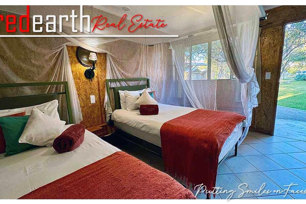 A twin bedroom featuring tiled flooring, wood-paneled walls, and direct access to an outdoor garden area through a glass door.