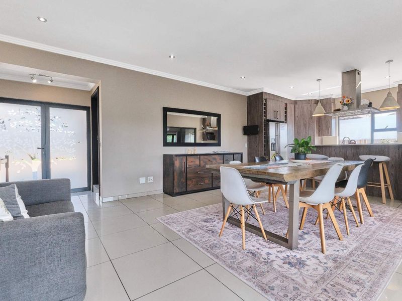 Spacious open-plan living and dining area featuring modern porcelain tiling, recessed lighting, and a contemporary kitchen with a central island and built-in cabinetry.