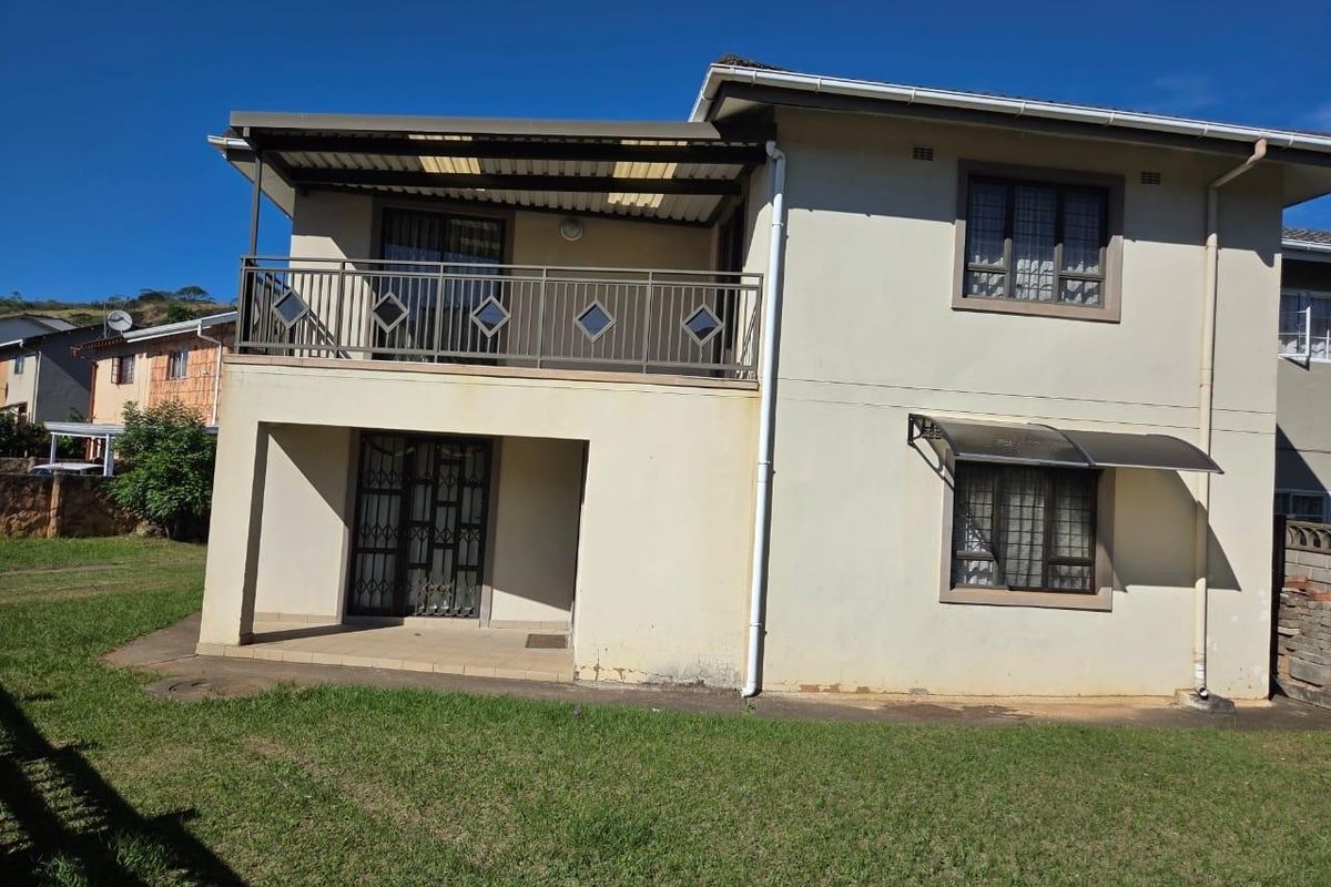 Rear view of a two-story house featuring a covered ground-floor patio, an upper-level balcony with metal railing, and security window treatments.