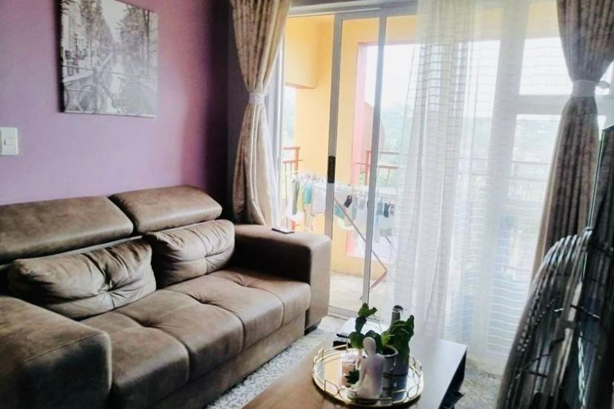 A cozy living room featuring tiled flooring and a large sliding glass door that provides access to an outdoor balcony area.