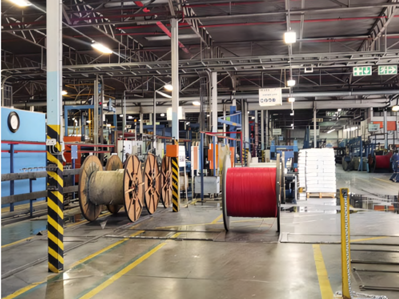 Spacious industrial warehouse facility featuring high ceilings, exposed steel trusses, overhead lighting, and concrete flooring suitable for manufacturing or storage operations.
