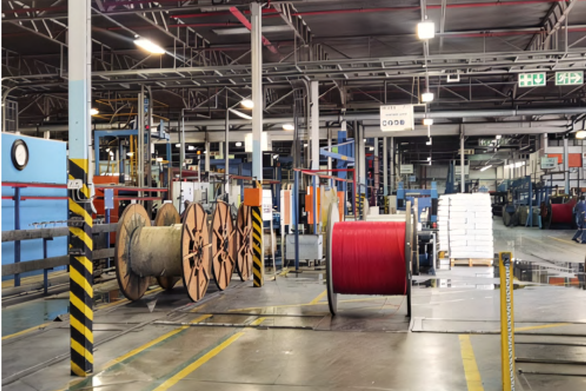 Spacious industrial warehouse facility featuring high ceilings, exposed steel trusses, overhead lighting, and concrete flooring suitable for manufacturing or storage operations.