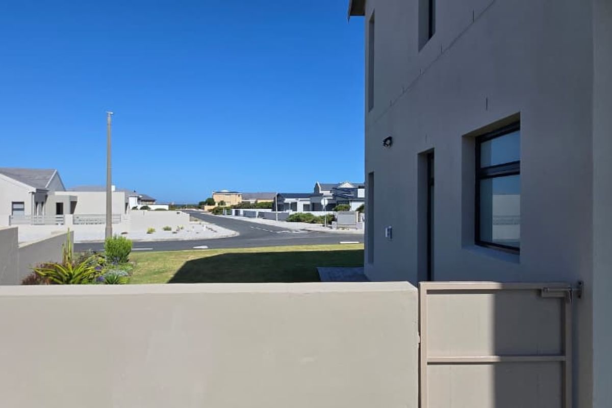 A view of the side exterior of the property, featuring a boundary wall, pedestrian gate, and outdoor tap, overlooking the neighbourhood street.