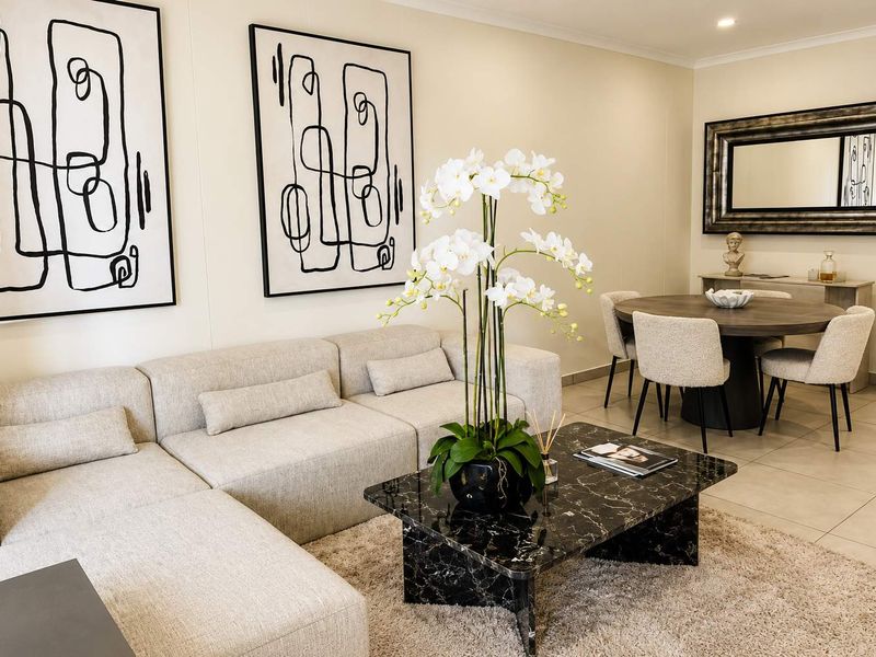 A well-presented open-plan living and dining area featuring neutral tiled flooring and modern recessed downlighting, creating a bright and cohesive living space.