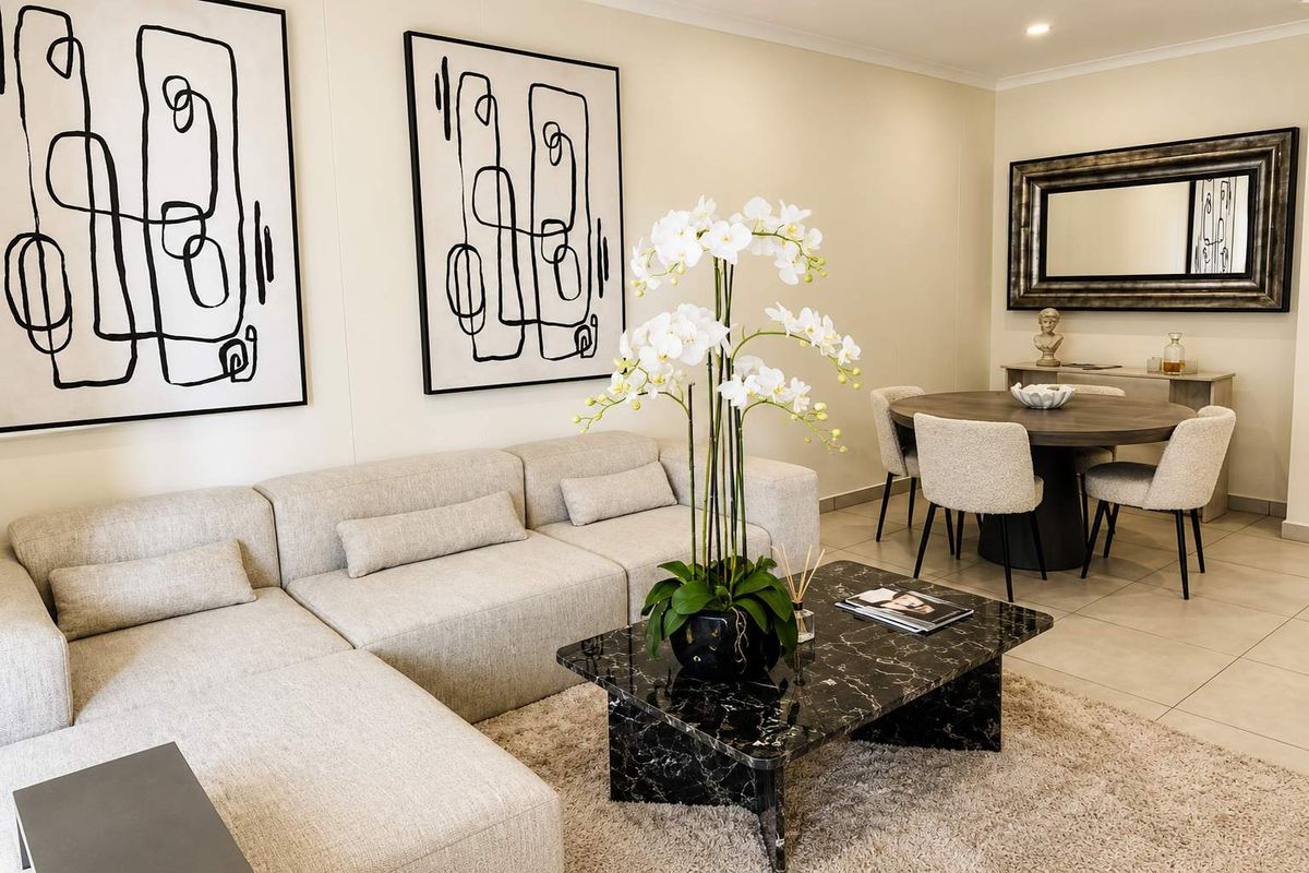 A well-presented open-plan living and dining area featuring neutral tiled flooring and modern recessed downlighting, creating a bright and cohesive living space.