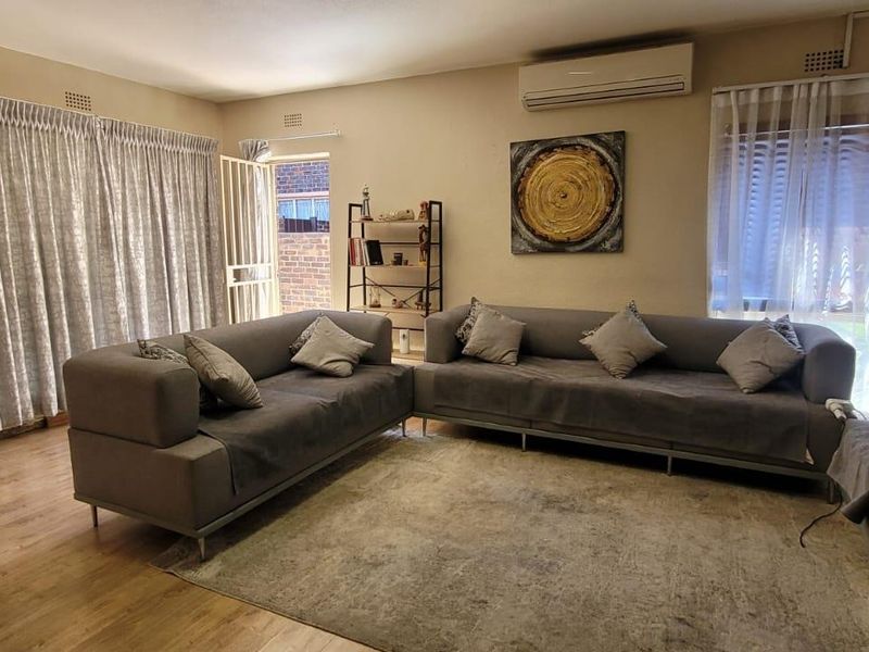 Spacious living room featuring laminate flooring, an air conditioning unit, and direct access to an outdoor area through a security gate.