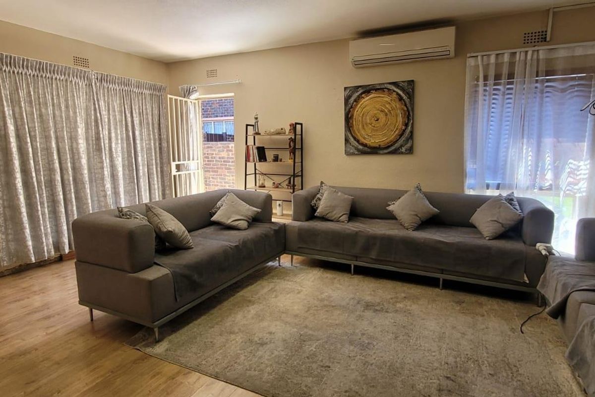 Spacious living room featuring laminate flooring, an air conditioning unit, and direct access to an outdoor area through a security gate.
