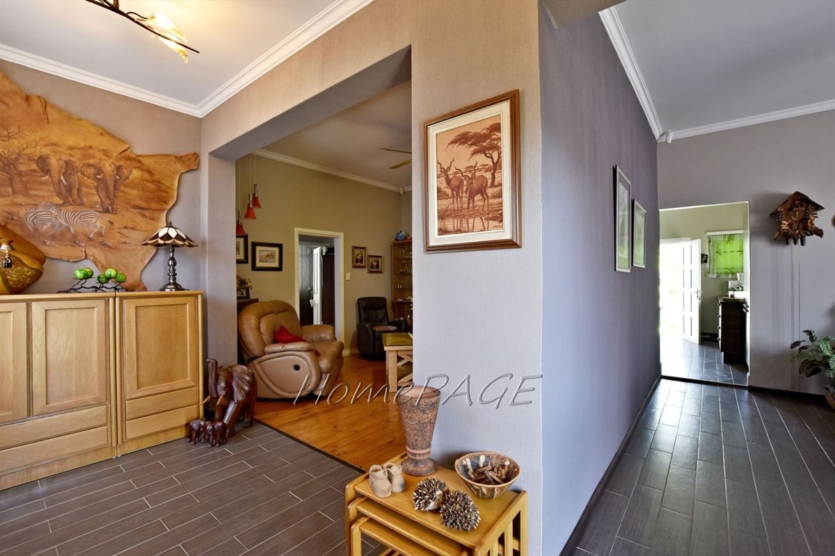 An interior view showing a transition between a tiled entrance area and a living space with wooden flooring, featuring crown molding and neutral wall tones.