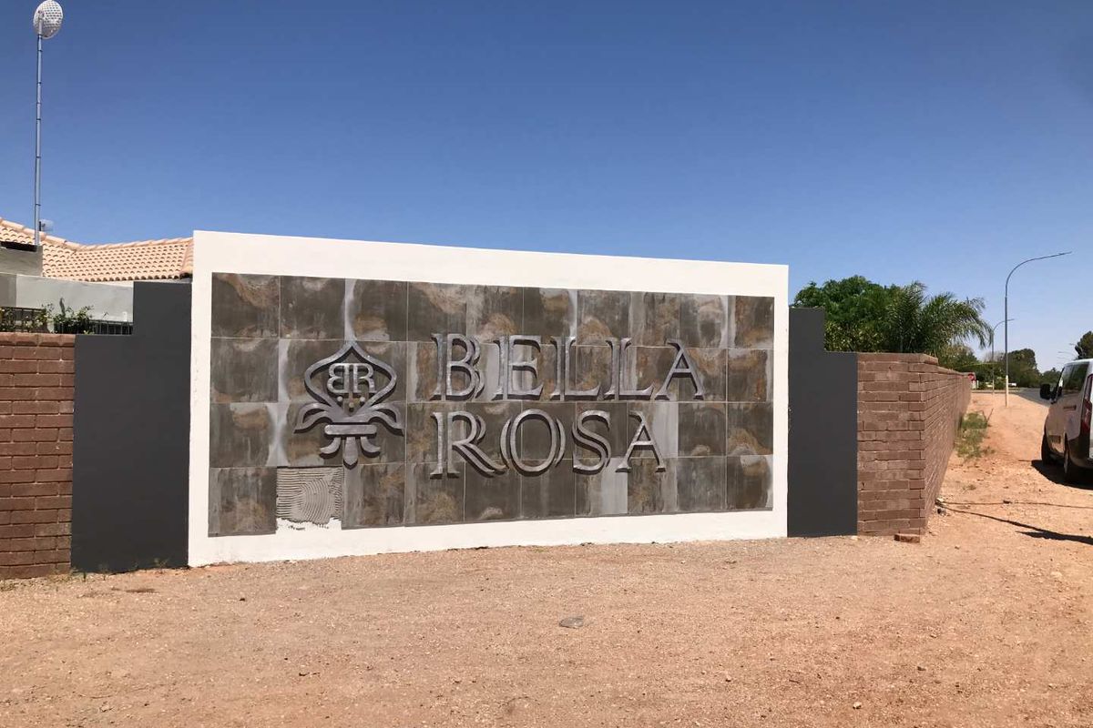 Entrance signage wall for Bella Rosa estate featuring brick and tiled finishes, showing minor maintenance requirements on the signage panel.