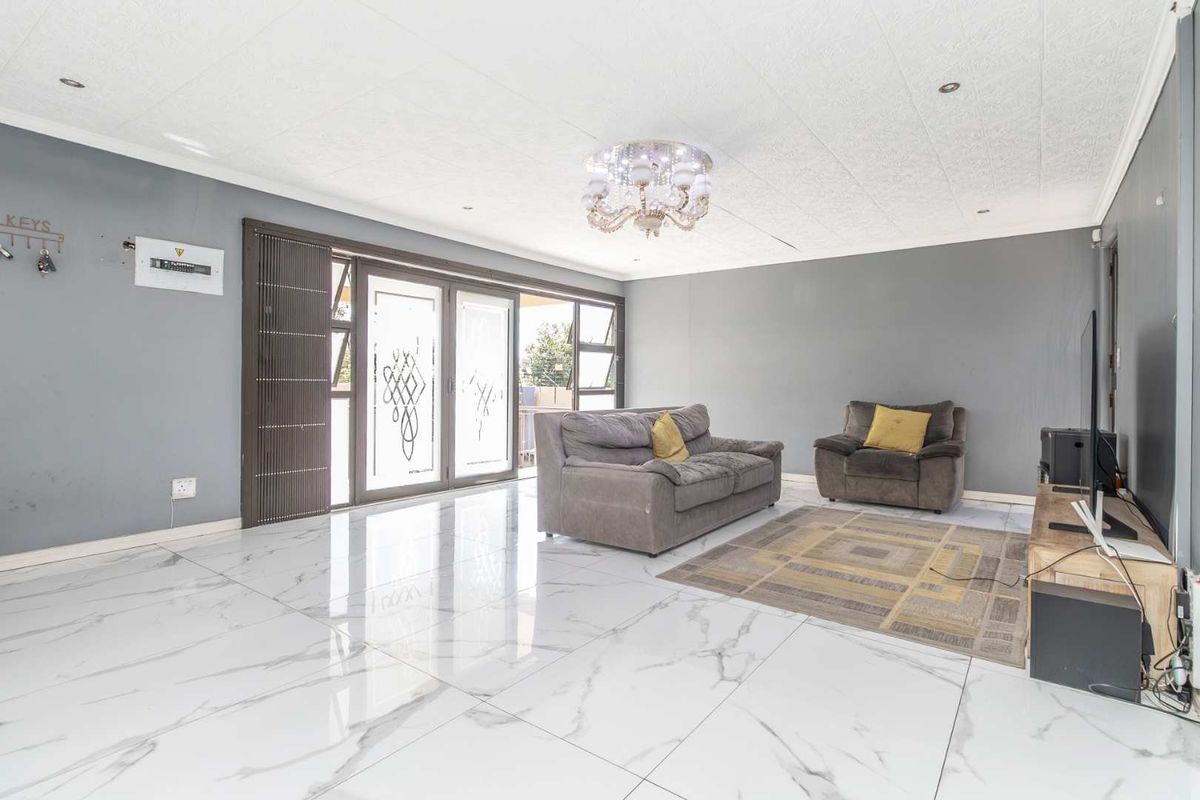 Spacious living room featuring large marble-look floor tiles, recessed lighting, and sliding glass doors providing access to the outdoor area.