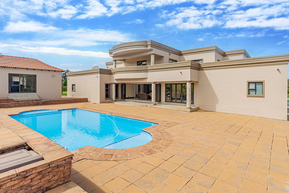 Spacious rear exterior view featuring a large swimming pool, paved patio area, and a multi-level residence with balconies and sliding glass doors.