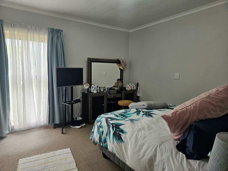 A functional bedroom featuring carpeted flooring and a sliding glass door with curtain treatments, providing natural light and access to the exterior.