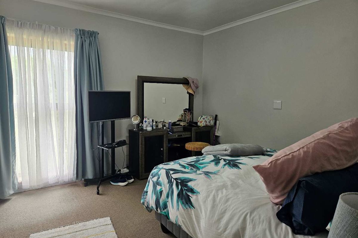 A functional bedroom featuring carpeted flooring and a sliding glass door with curtain treatments, providing natural light and access to the exterior.
