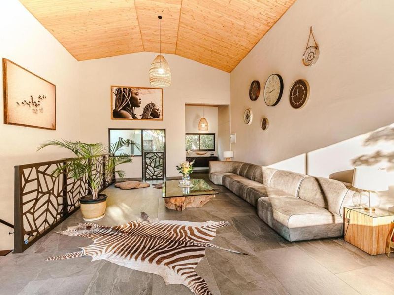 Spacious living area featuring a high vaulted timber ceiling, stone tile flooring, and a decorative metal balustrade overlooking the lower level.