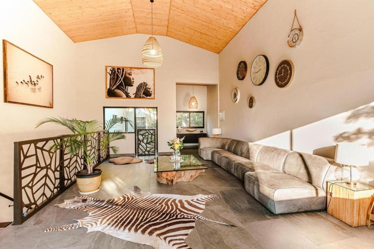 Spacious living area featuring a high vaulted timber ceiling, stone tile flooring, and a decorative metal balustrade overlooking the lower level.