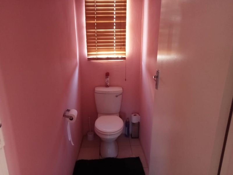 A compact bathroom featuring a standard toilet and window with venetian blinds.