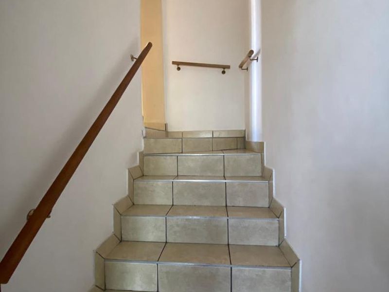 A functional staircase featuring tiled steps and wooden handrails, providing access between levels within the apartment.