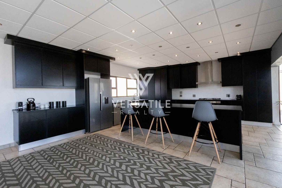 Modern kitchen featuring dark cabinetry, a central island, tiled flooring, and recessed lighting, providing a functional and contemporary cooking and dining space.