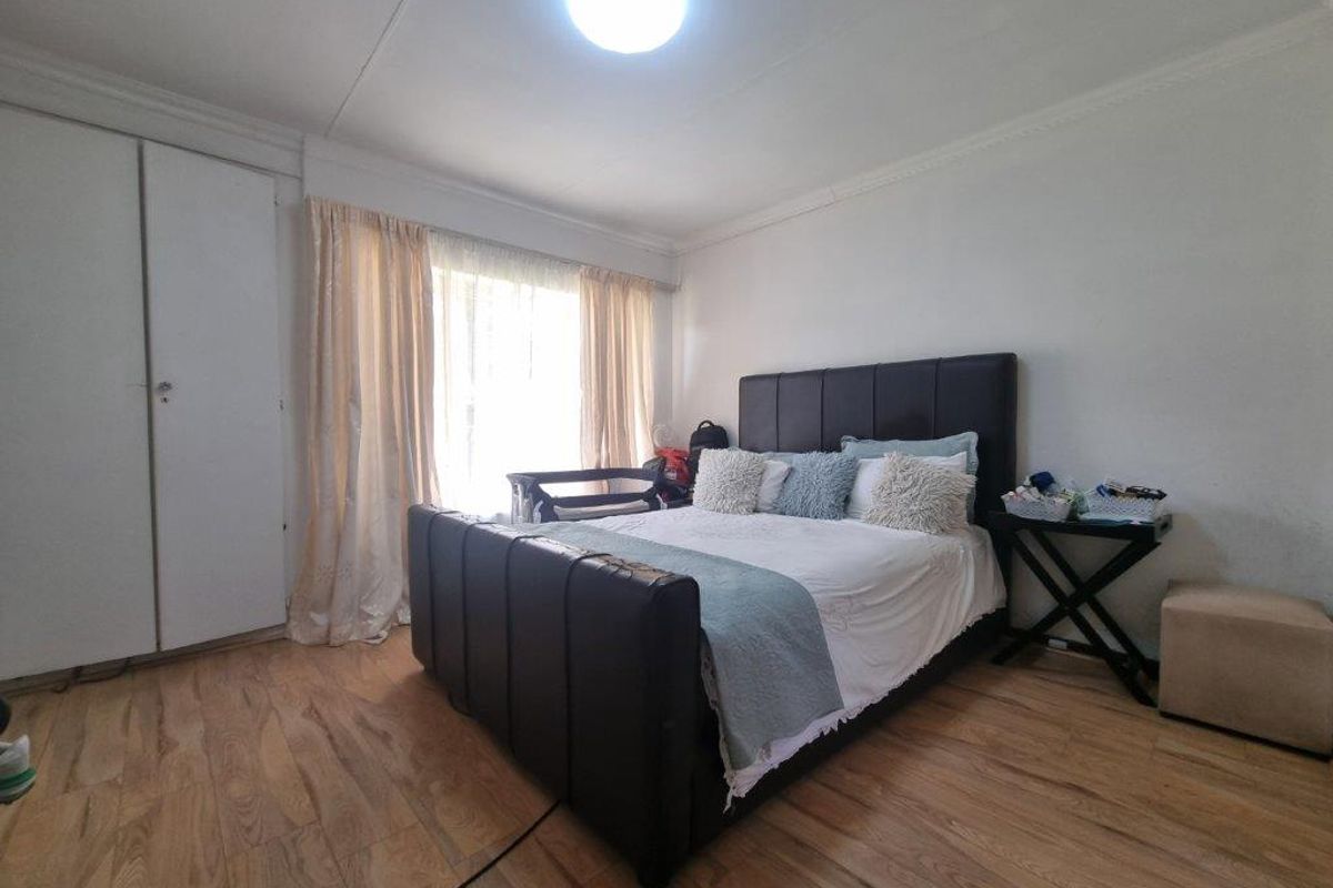 A bedroom featuring laminate flooring and built-in cupboards, offering a functional space with natural light.