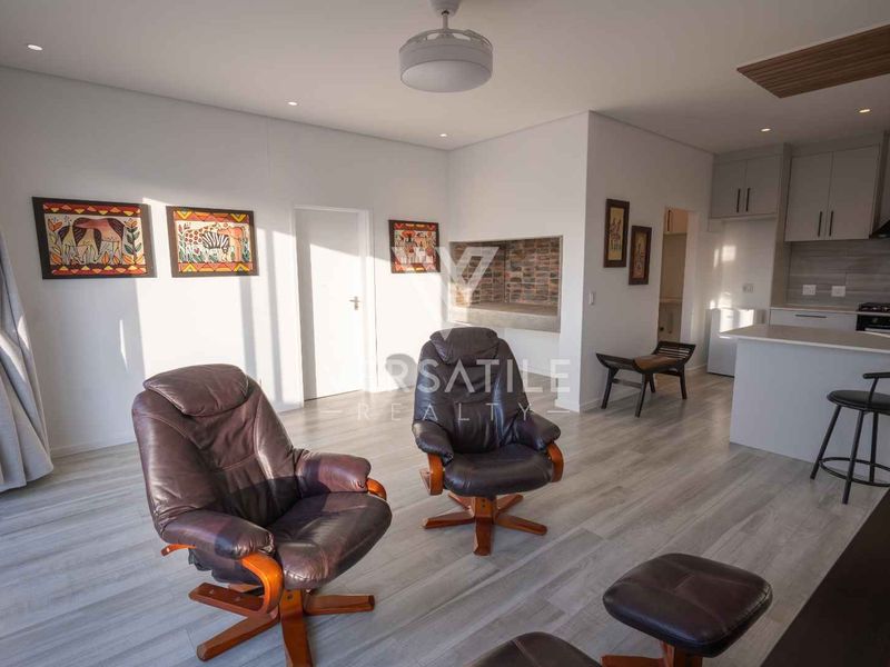 Modern open-plan living area featuring a contemporary kitchen with built-in appliances, sleek cabinetry, and light wood-look laminate flooring throughout.