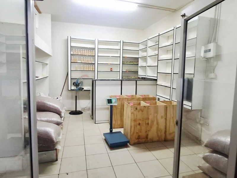 A functional utility or storage space featuring built-in shelving units, a service counter, and tiled flooring, accessible via glass partition doors.