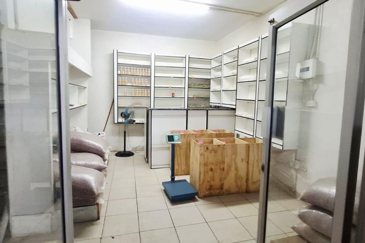 A functional utility or storage space featuring built-in shelving units, a service counter, and tiled flooring, accessible via glass partition doors.